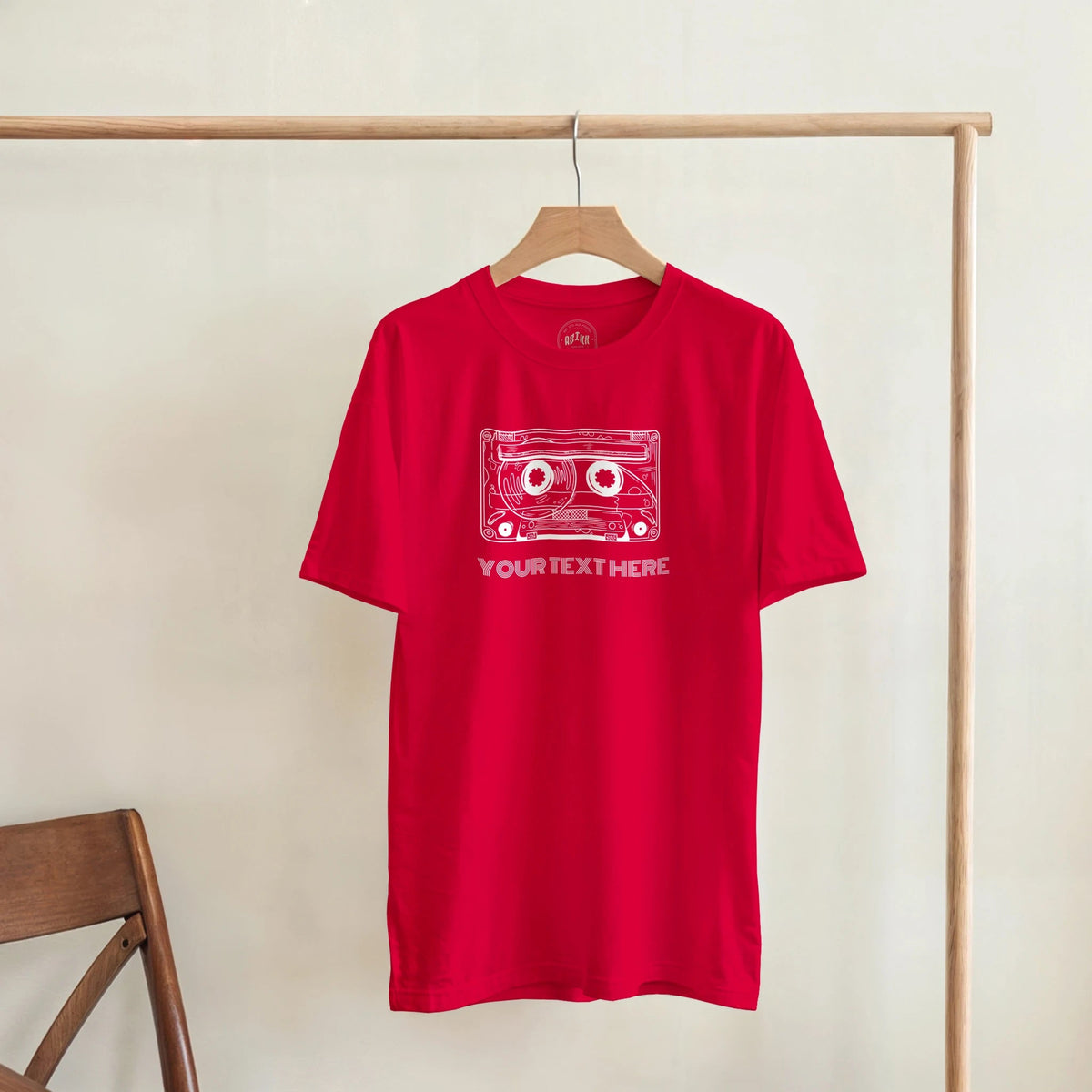 Red T-shirt with a retro cassette and sample text “YOUR TEXT HERE”, front view.